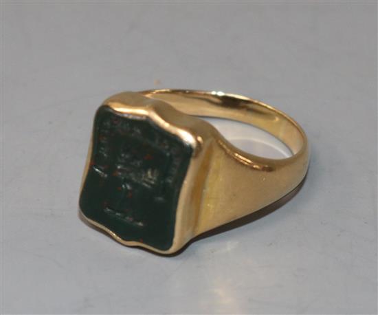 An early 20th century 18ct gold and bloodstone set signet ring, the matrix carved with crest and motto, size R.